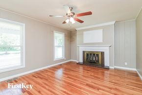Florissant house for rent - an empty living room with a fireplace and a ceiling fan