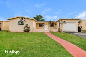 Lauderdale Lakes house for rent - a beige house with a driveway and a lawn