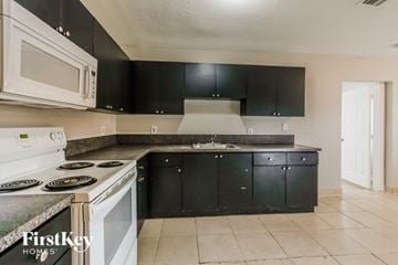 Lauderdale Lakes house for rent - a kitchen with black cabinets and white appliances and a white stove