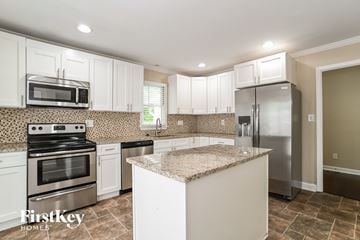 Charlotte house for rent - a white kitchen with stainless steel appliances and a granite counter top