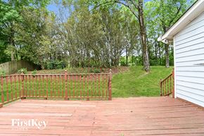Charlotte house for rent - a backyard deck with a fence and a hill with trees