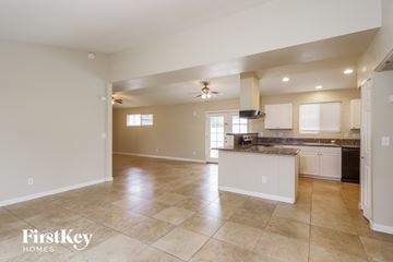 Phoenix house for rent - an open kitchen and living room with white cabinets and tile flooring
