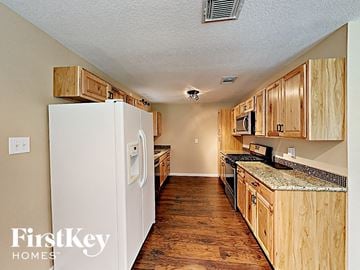 Spring house for rent - a kitchen with wooden cabinets and a white refrigerator