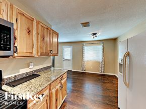 Spring house for rent - an empty kitchen with wood cabinets and granite counter tops