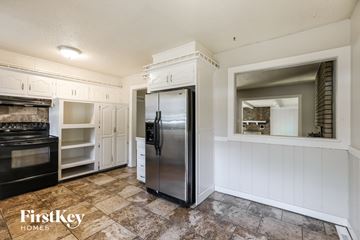 Independence house for rent - a kitchen with white cabinets and a stainless steel refrigerator