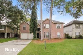Humble house for rent - a brick house with two garage doors and a lawn