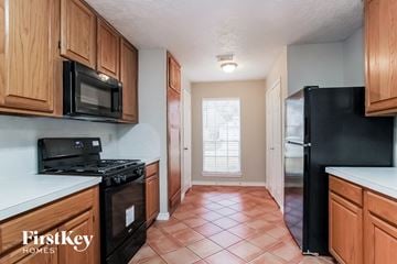 Humble house for rent - a kitchen with wood cabinets and black appliances and a window