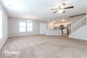 Indianapolis house for rent - an empty living room with a ceiling fan and a kitchen
