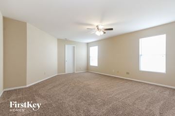 Indianapolis house for rent - a spacious living room with carpet and a ceiling fan