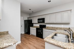 Dallas house for rent - a kitchen with white cabinets and black appliances