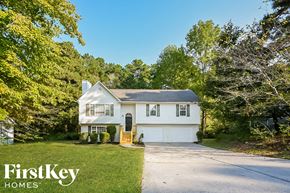 Kennesaw house for rent - A white house with a garage is surrounded by trees.