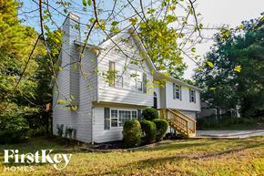 Kennesaw house for rent - A white house with a yellow staircase is surrounded by trees.