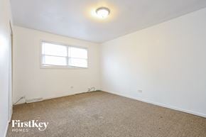 Lansing house for rent - a bedroom with white walls and a window and a carpet