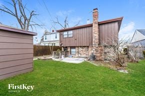 Lansing house for rent - a backyard with a brick house and a yard with grass and a fence