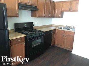 Midlothian house for rent - an empty kitchen with black appliances and wooden cabinets