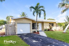 Pompano Beach house for rent - a home with palm trees and a white garage door