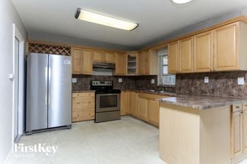 Pompano Beach house for rent - a kitchen with wooden cabinets and a stainless steel refrigerator