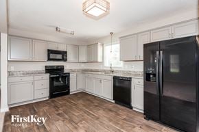Gastonia house for rent - a kitchen with white cabinets and black appliances
