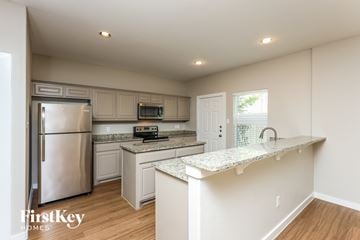 Dallas house for rent - a kitchen with white cabinets and granite counter tops and a stainless steel refrigerator