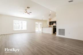 North Port house for rent - A spacious room with a ceiling fan and wooden flooring.