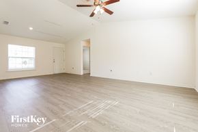 North Port house for rent - A spacious room with a ceiling fan and wooden flooring.