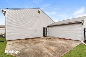Indianapolis house for rent - A large white garage with a roll-up door is situated in a grassy area.