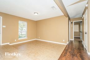 Irving house for rent - A room with beige walls and wooden flooring, with a window and a door visible.