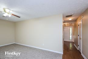 Cumming house for rent - an empty living room with a ceiling fan and a door to a hallway