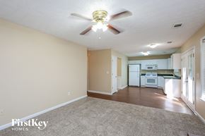 Cumming house for rent - an empty living room with a ceiling fan and a kitchen