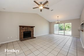 Fort Worth house for rent - A spacious living room with a fireplace and a ceiling fan.