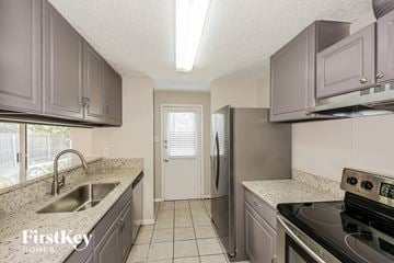 Fort Worth house for rent - A kitchen with a stove top oven and a refrigerator.
