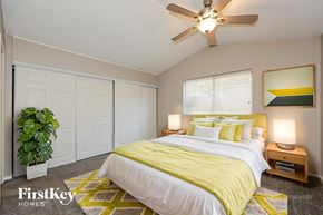 Fort Worth house for rent - A bedroom with a bed, a ceiling fan, and a plant.