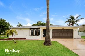Cape Coral house for rent - a home with a palm tree in the yard and a garage door