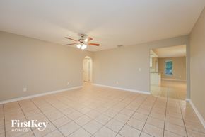 Cape Coral house for rent - a empty living room with a ceiling fan and tiled floors