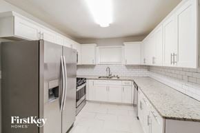 Decatur house for rent - a kitchen with white cabinets and a stainless steel refrigerator