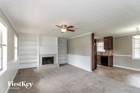 Marietta house for rent - A spacious living room with a fireplace and a ceiling fan.