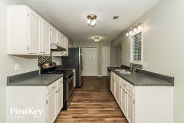 Douglasville house for rent - A kitchen with white cabinets and a black countertop.