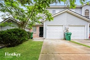 Decatur house for rent - a white house with a white garage door and a green trash can