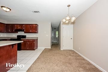 Decatur house for rent - a kitchen with brown cabinets and white flooring and a hallway with a white door