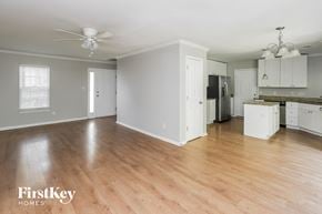 Charlotte house for rent - A spacious room with wooden floors and a kitchen area in the background.