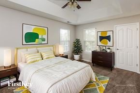 Charlotte house for rent - A bedroom with a large bed, a ceiling fan, and two framed artworks on the wall.