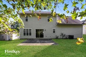 Charlotte house for rent - A house with a grey siding and a black door is surrounded by green grass.