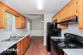 Rex house for rent - a kitchen with black appliances and wooden cabinets