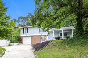 Conley house for rent - a white and brick house on a hill with trees
