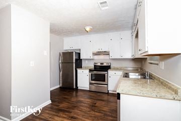 Conley house for rent - a kitchen with white cabinets and stainless steel appliances