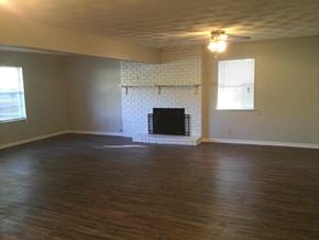 Dallas house for rent - an empty living room with a fireplace and wood floors