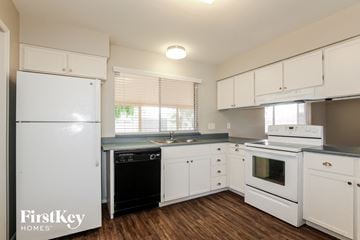 Phoenix house for rent - a kitchen with white cabinets and white appliances and a black dishwasher