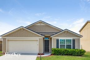 Green Cove Springs house for rent - a beige house with a garage door and a lawn