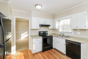 Smyrna house for rent - a kitchen with white cabinets and a black stove and refrigerator