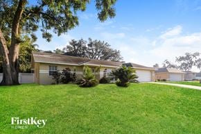 Lakeland house for rent - A house with a lawn and trees in front of it.
